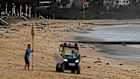 A North Steyne Surf Life Saving Club member erects a sign notifying the public that Manly Beach is closed.