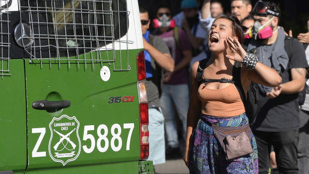 A demonstrator shouts slogans near a police vehicle near Costanera shopping mall in the business district of Santiago on Wednesday. 