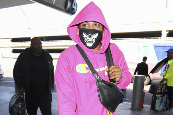 Rapper Nelly wears his skull mask with a bright pink hoodie.
