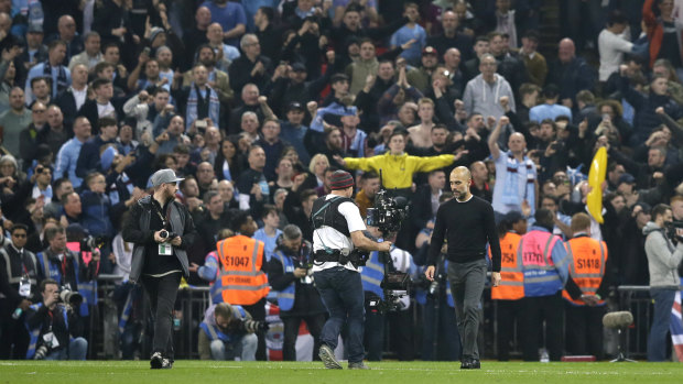 Manchester City coach Pep Guardiola leaves the field after celebrating with supporters.