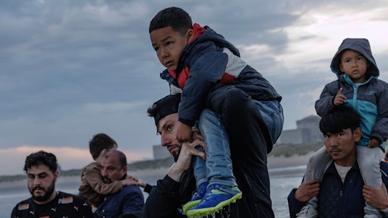 Migrant families wade into the sea at Gravelines, France, in an attempt to board a small boat heading to the UK.