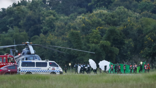 An emergency team rushes to a helicopter believed to be carrying one of the rescued boys from the flooded cave.