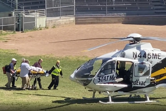 Salman Rushdie is taken on a stretcher to a helicopter.