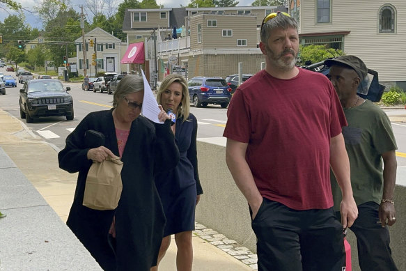 Denise Lodge (left) covers her face as she walks from the courthouse.