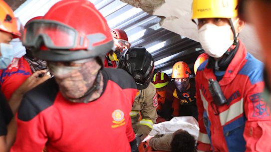 Rescuers carry a survivor who was pulled out from the rubble after a building under construction collapsed at an Islamic boarding school in Sidoarjo, East Java, Indonesia, Wednesday, Oct. 1, 2025. (AP Photo/Alam Syahirul)
