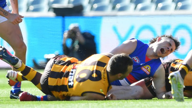 Toby McLean grimaces in pain after a tackle by Hawk Jonathon Ceglar. 