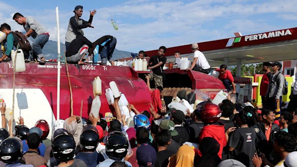 People take fuel from a truck on  Sunday following earthquakes and a tsunami in Palu two days earlier.