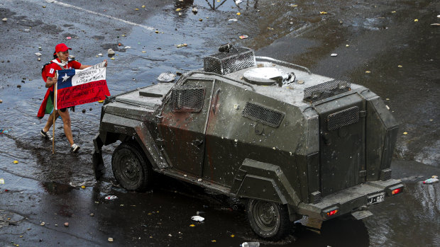 A demonstrator holds a Chilean flag toward an armoured police vehicle Chile's capital, Santiago, this week.