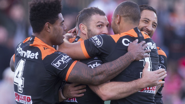 Old firm: Robbie Farah and Benji Marshall join a Tigers huddle after a try to Luke Brooks against the Dragons on Sunday.