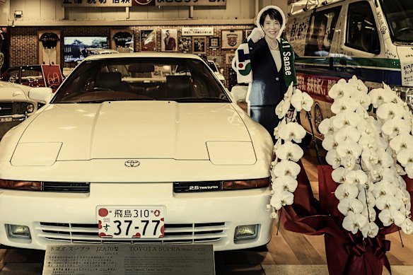 A cutout of Takaichi between a former campaign car and the twin-turbo Toyota Supra model she once drove, in the Nara Toyota automobile museum in October.