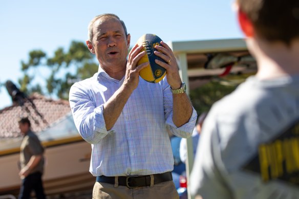 Roger Cook kicks a footy with the Davies family, who say they welcome the government’s Student Assistance Payment.