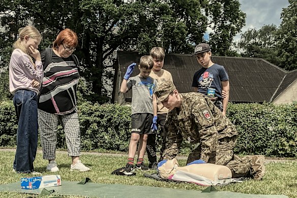 In Latvia, a member of the volunteer army shows first aid to visitors at a Civil Defence Information Day in June 2024.