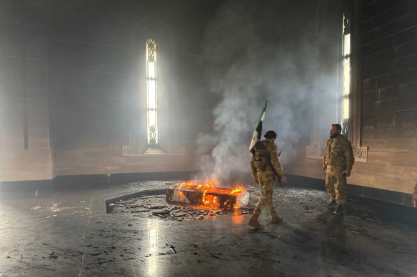Rebel fighters stand next to the burning grave site of Syria’s late president Hafez al-Assad at his mausoleum.