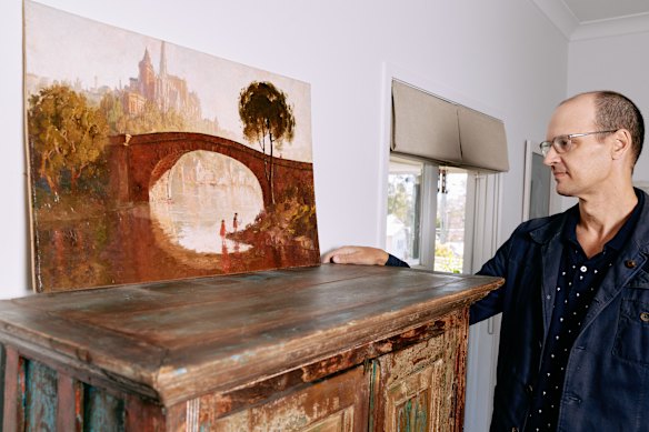 Davin Grikis with his wife’s restored painting. Grikis turned to ChatGPT and Claude to help build a case for its being a Lloyd Rees.