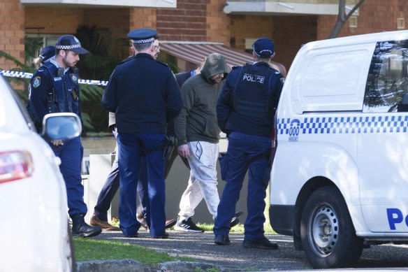 Police lead away a man at a block of units in Dee Why.