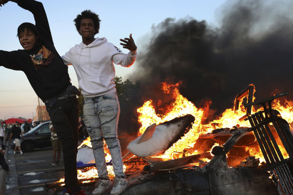 Young men stand atop a burning car in the Target parking lot.