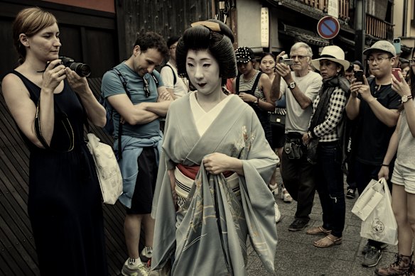 A geisha is surrounded by toursts as she walks in Kyoto. 