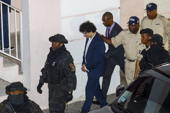 Sam Bankman-Fried, center, is escorted out of the District Court building a day after his arrest in Nassau, Bahamas.