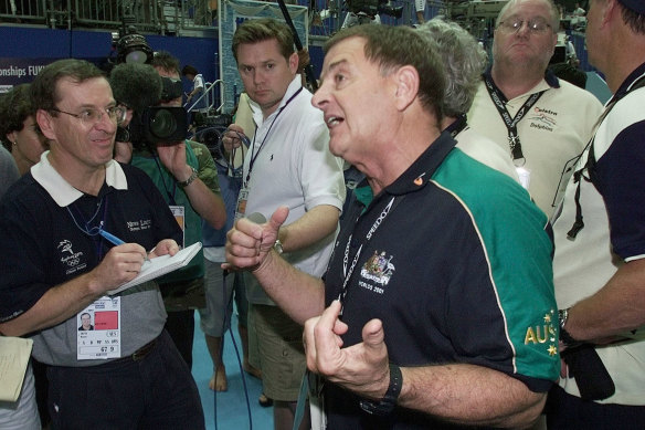 Australian swimming team head coach Don Talbot talks to reporters, including Wayne Smith (left), after it was announced that the Australian women’s 4x200m freestyle relay team had been disqualified.