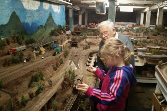 The late Raymond Gray shows his granddaughter the model train set he built under his house.