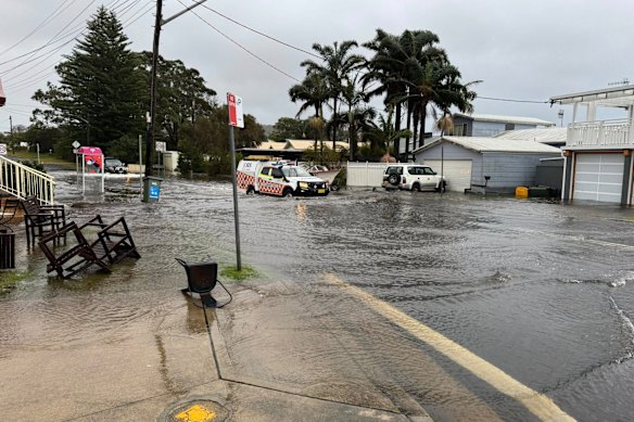 An SES vehicle drives through floodwater in Burrill Lake, where water has inundated homes and sparked emergency warnings.