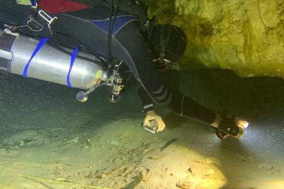 Aquatic archaeologist Octavio del Rio films a pre-historic human skeleton partly covered by sediment in an underwater cave in Tulum, Mexico.