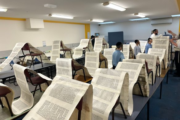 Members of the Adass Israel community inspect Torah scrolls damaged in Friday’s synagogue firebombing.