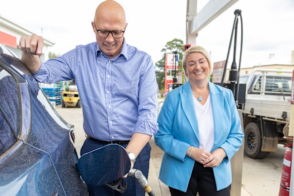 Dutton fills up a car with petrol at the Ampol Carrick petrol station in Tasmania as Lyons candidate Susie Bower looks on.