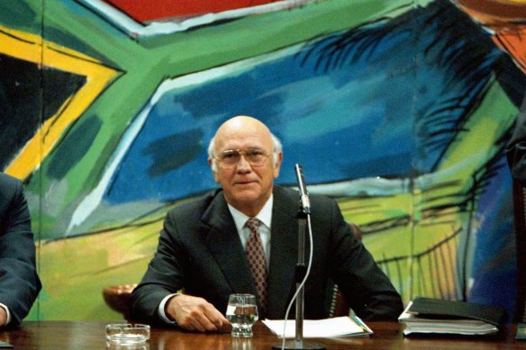 Former president and leader of the National Party F. W. de Klerk, discusses his resignation below a mural of the new South African flag in 1997.