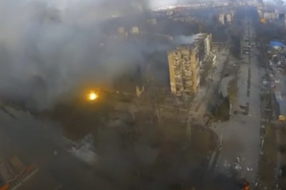 An aerial view of dark smoke rising from several buildings and a flash of light from an apparent blast in Mariupol, Ukraine. 