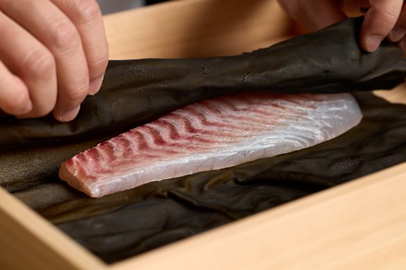 Yu wraps a fillet of fish in kombu.
