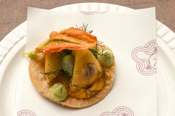 Squash tostada, a one-bite morsel topped with smoky grilled squash and zucchini flower.