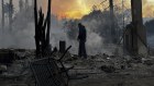 A resident hoses down hot spots in a fire-ravaged property.