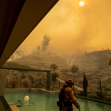 In California, an Orange County firefighter prepares to defend a home as the Silverado fire approaches a neighborhood in October 2020.
