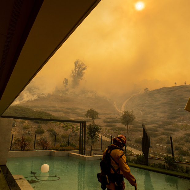 In California, an Orange County firefighter prepares to defend a home as the Silverado fire approaches a neighborhood in October 2020.