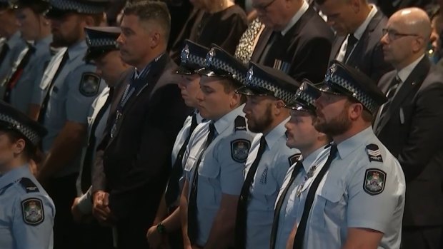 Police stand for a minute’s silence at the memorial service for fallen officers Rachel McCrow and Matthew Arnold.