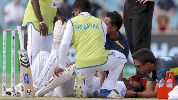 'Scary' moment: Medical staff assist Sri Lanka's Dimuth Karunaratne after being struck by a delivery from Pat Cummins.