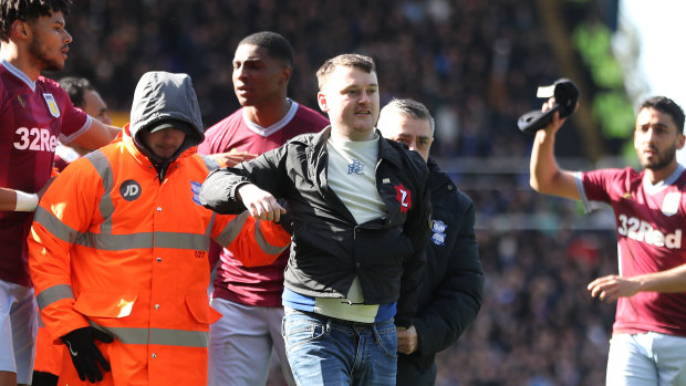 Paul Mitchell is led from the pitch by officials after his cowardly attack on Aston Villa's Jack Grealish.