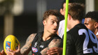 Jamie Elliott of the Magpies handballs while being tackled during a Collingwood Magpies AFL training session at Holden Centre on Monday.