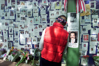 A man rests his head against a pole at Bellevue Hospital as he pauses in front of a wall of pictures of people missing in New York on September 15, 2001.  Relatives and friends of people missing as a result of the collapse of the World Trade Center are posting pictures on the wall.    
