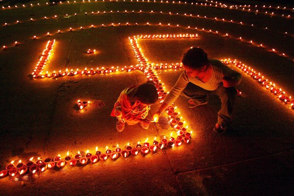 Children light lamps in the shape of the swastika on the eve of Hindu festival of Diwali.