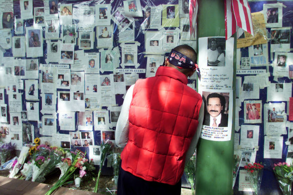 A man rests his head against a pole at Bellevue Hospital as he pauses in front of a wall of pictures of people missing in New York on September 15, 2001.  Relatives and friends of people missing as a result of the collapse of the World Trade Center are posting pictures on the wall.    