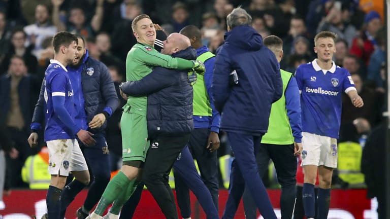 Oldham Athletic's players and staff celebrate after beating Fulham at Craven Cottage in the third round of the FA Cup on Sunday.