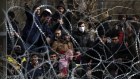 Migrants stand behind a fence near the Kastanies border gate at the Greek-Turkish border.