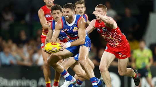 Marcus Bontempelli of the Bulldogs is tackled by Matt Rowell of the Suns.