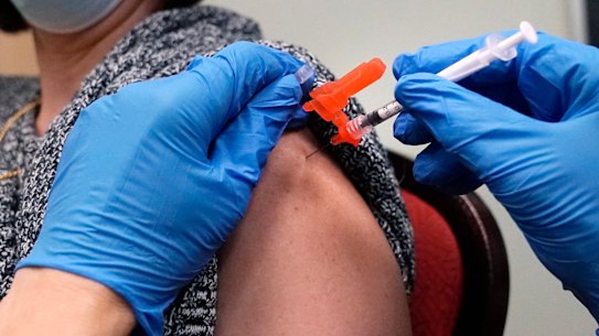 A woman receives a COVID-19 vaccine injection by a pharmacist at a clinic in Massachusetts.