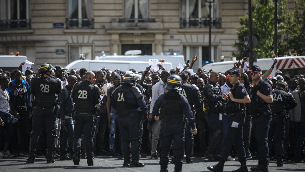 French police officers hold back protesters and migrants outside the Pantheon monument.