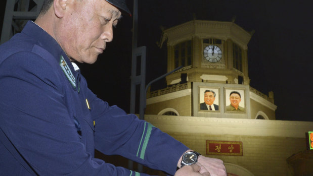 A man adjusts his wristwatch in front of a clock of the Pyongyang Station in Pyongyang, North Korea, early on Saturday.