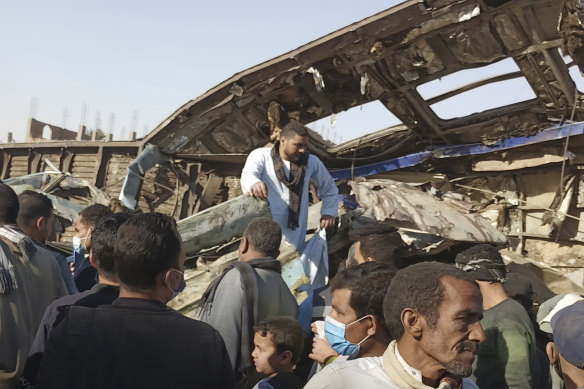 Villagers look for remains of victims around mangled train carriages at the scene of a train accident in Sohag,Egypt