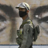 A soldier guards a voting poll at a school that has the eyes of the late President Hugo Chavez painted on a wall during elections to choose members of the National Assembly in Caracas.